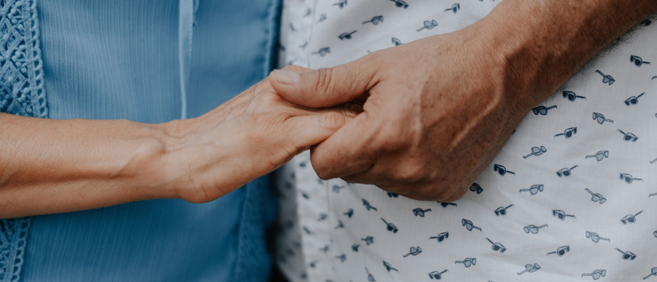 Close up of an elderly woman and an elderly man holding hands