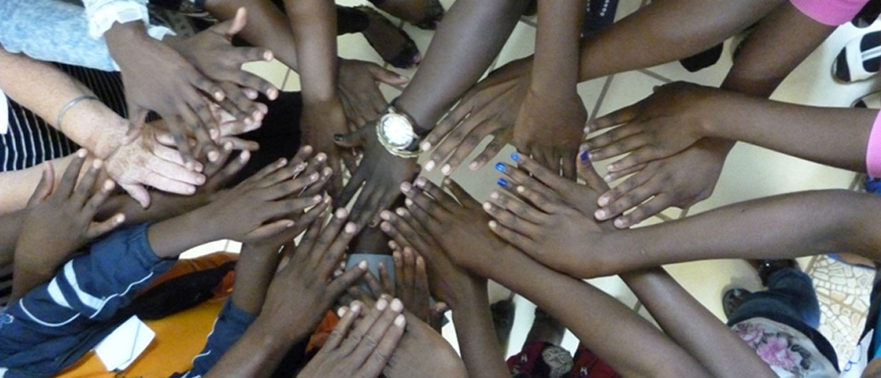 Hands touching other hands in a circle. Credit: Co-Production of a Support Group Curriculum for and with adolescent girls living with HIV, Zambart, ICRW & LSHTM, MAC AIDS Foundation