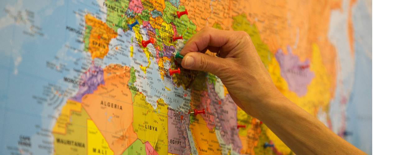 World map with someone holding a drawing pin. Credit: LSHTM