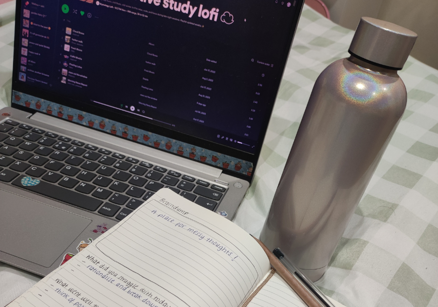 A laptop, a bottle and a notebook on a desk