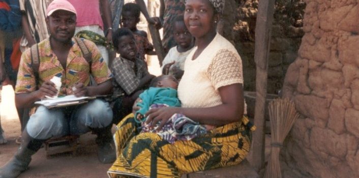 A fieldworker interviews a mother with her young baby