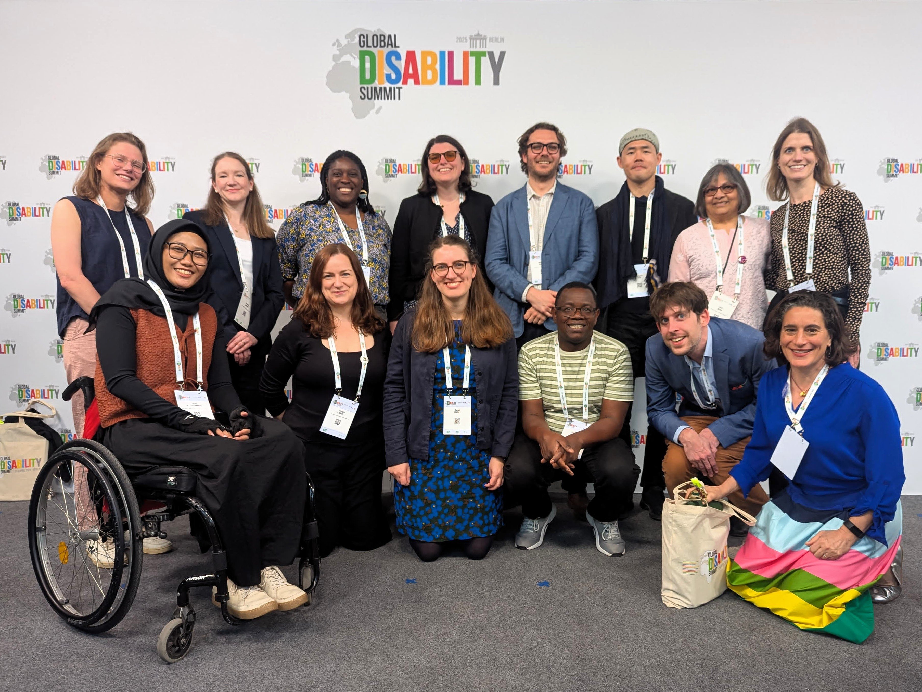 ICED team members at the Global Disability Summit 2025 pose for a photo in front of the GDA banner.