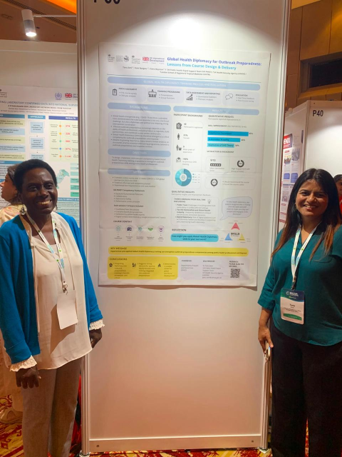 Two people standing either side of a conference poster smiling. 