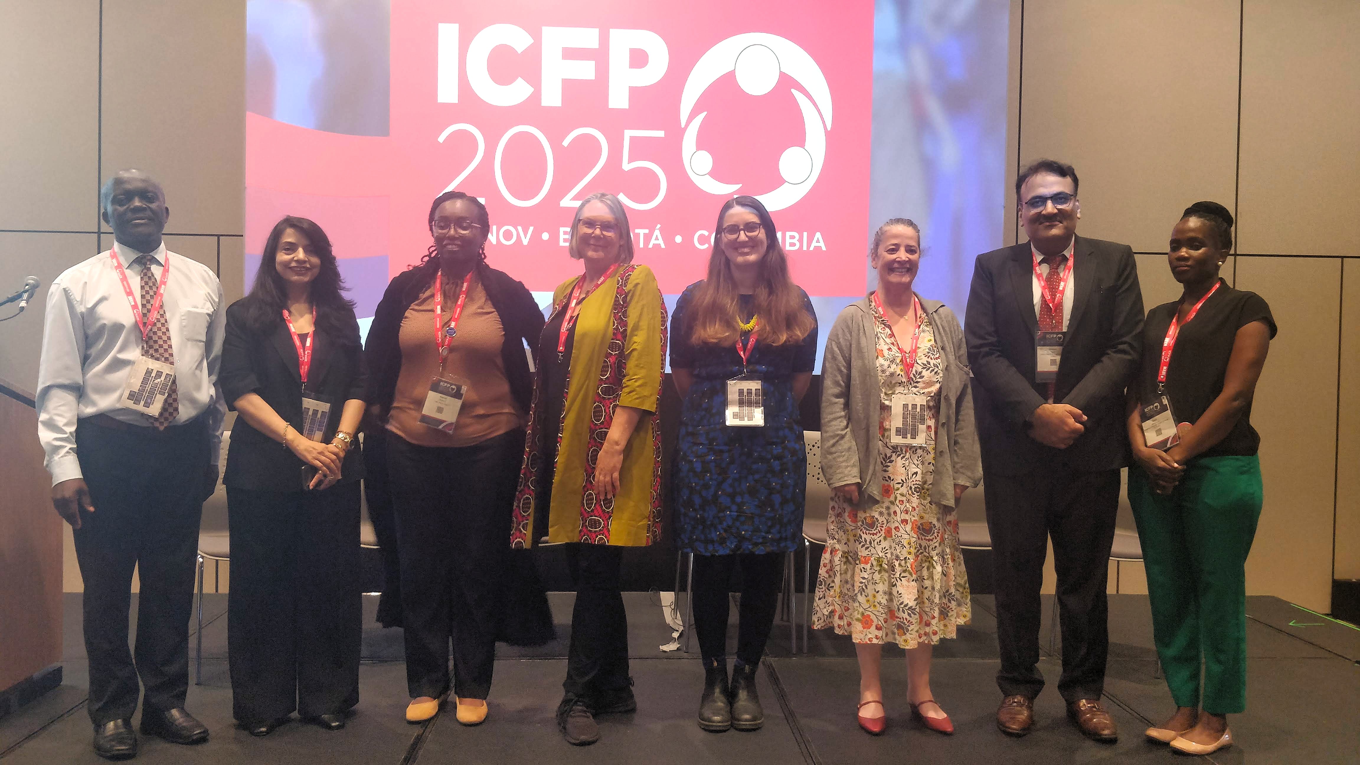 Sarah Marks poses for a group photos with attendees at the International Conference on Family Planning in Bogota, Colombia. The ICFO 2025 banner and logo are projected behind them.