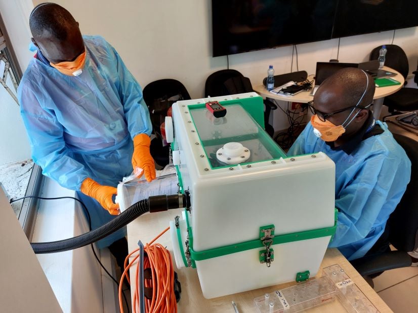 KEMRI Wellcome trust staff wearing PPE and operating a micobiology containment box during training.