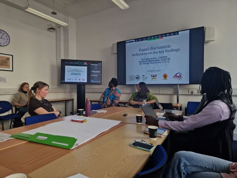 People sitting around a table in front of presentation on large projector screen. 