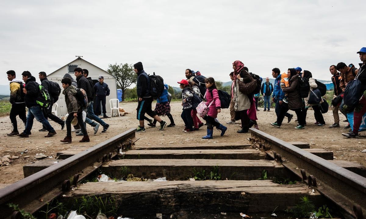 Caption: Migrants crossing train track Credit: UNHCR