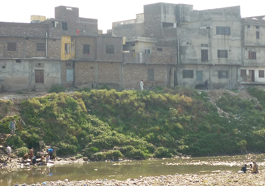 Rubbish and effluent flow into a river in Pakistan as people wash and bathe in the dirty water