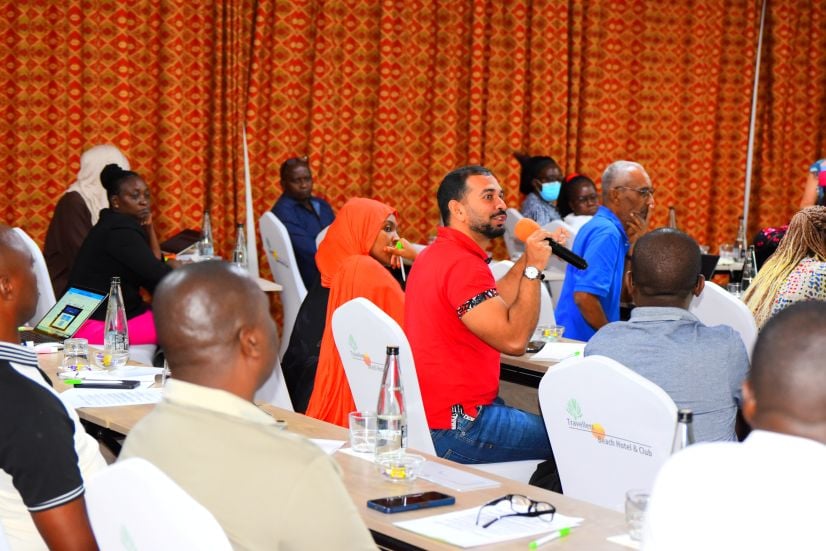 People sitting in a conference, with someone speaking into a microphone