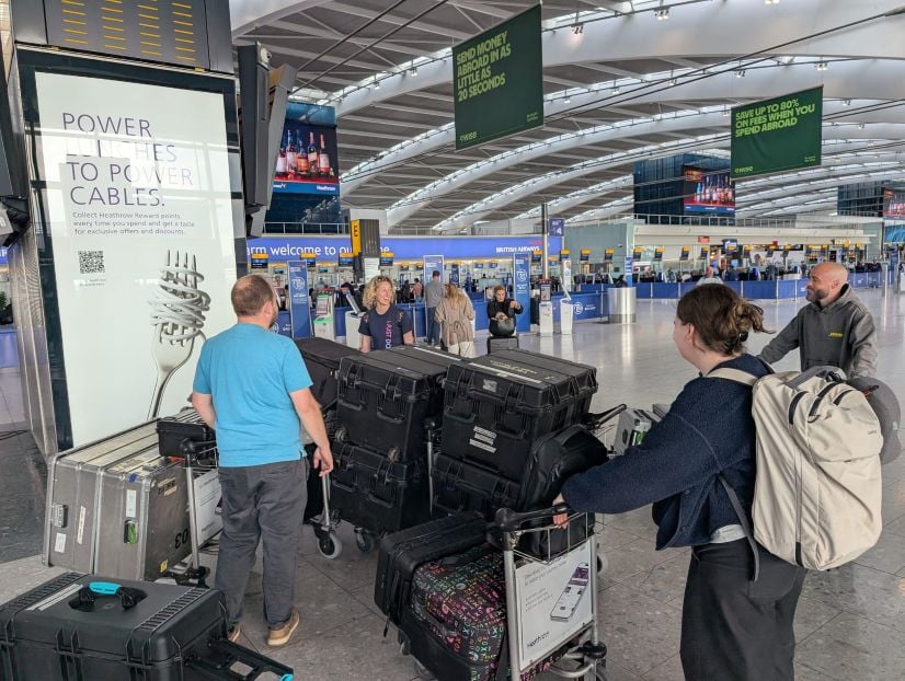 People standing in airport with luggage carts carrying large plastic boxes containing a rapid response mobile lab