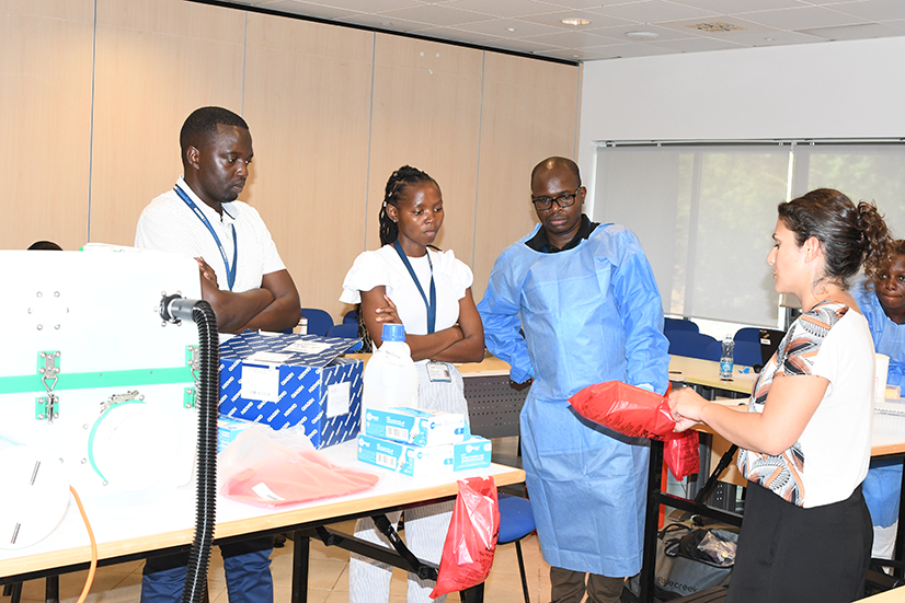 UK-PHRST staff demonstrating microbiology equipment to Kenya KEMRI Wellcome Trust staff donned in PPE.