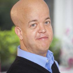 A headshot of Tom Shakespeare, who is wearing a blue shirt and a black jumper over it.