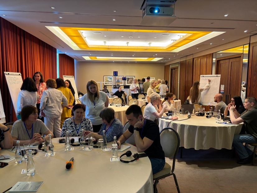 Workshop attendees sitting around tables and working at flipchart boards.
