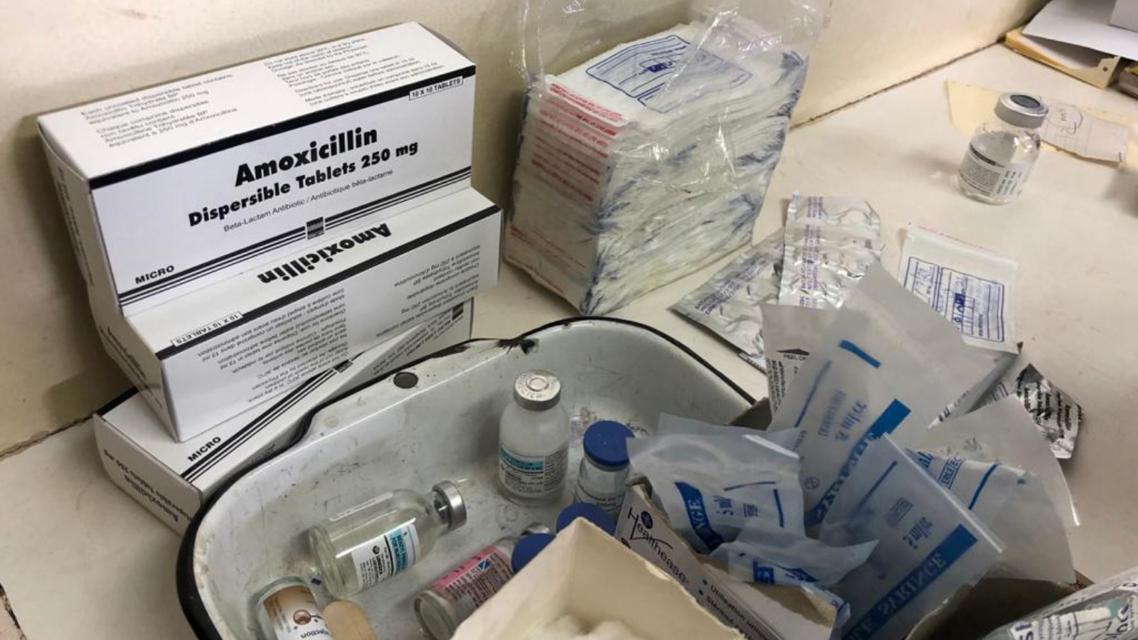 Boxes of antibiotics, vials and medical equipment on top of a table.