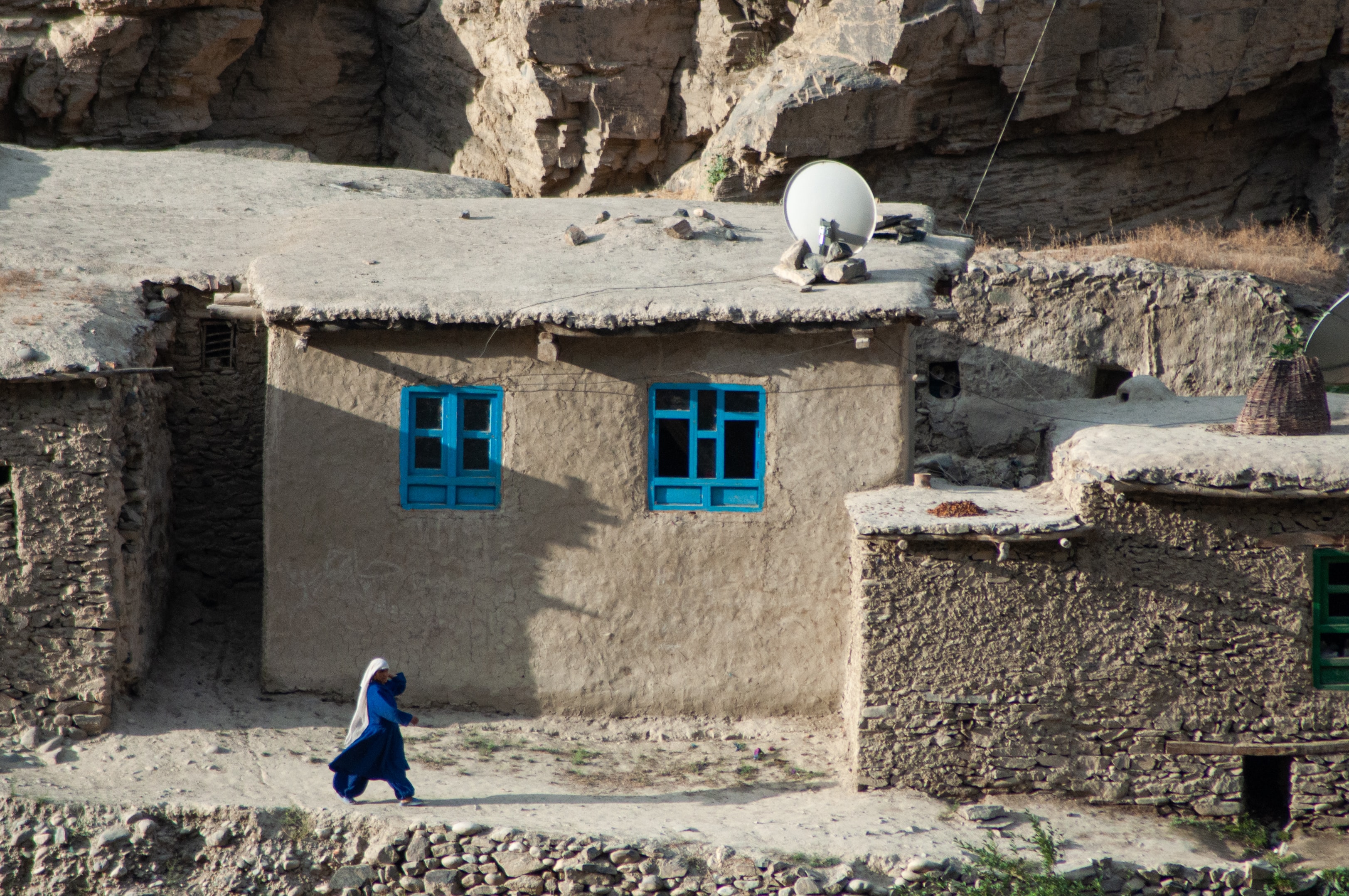 Woman walking in front of houses in Badakhshan, Afghanistan. Credit: Joel Heard/Unsplash