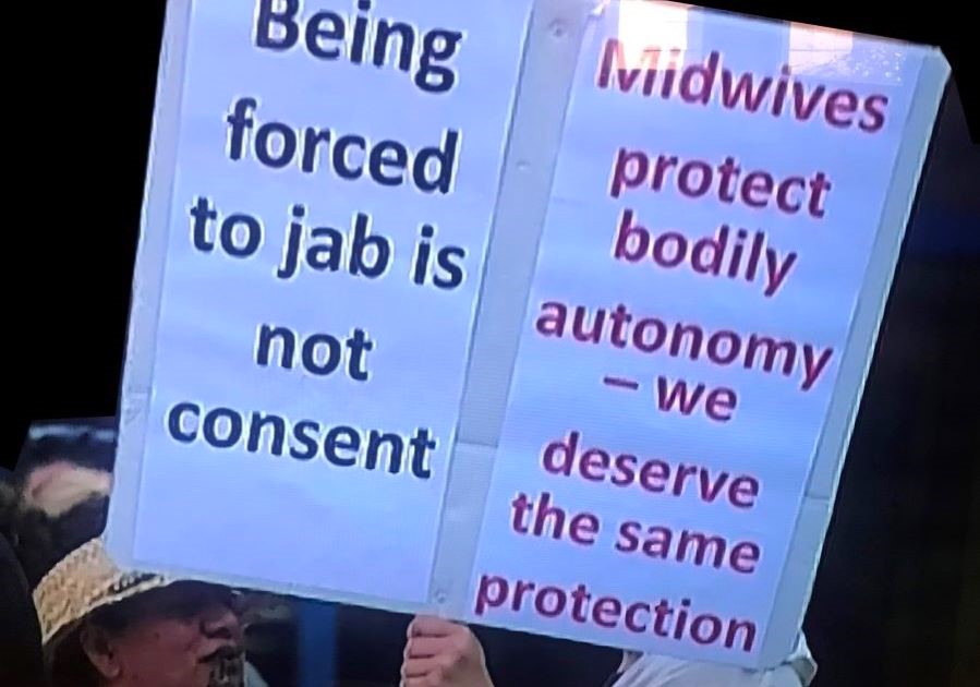 ​Alt text: A photograph of a placard stating ‘Being forced to jab is not consent – Midwives protect bodily autonomy – we deserve the same protection’