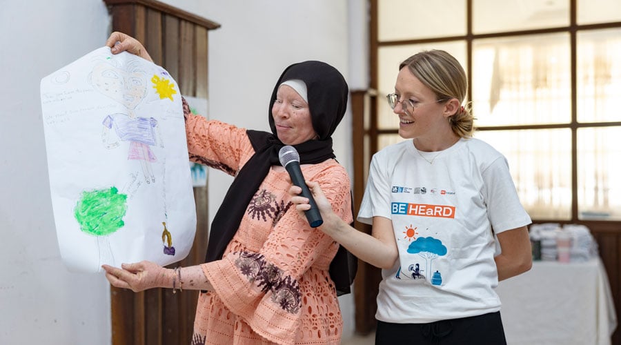 A participant sharing her painting, which showcases the effect of heat on her body and cooling mechanisms like seeking shade under trees.