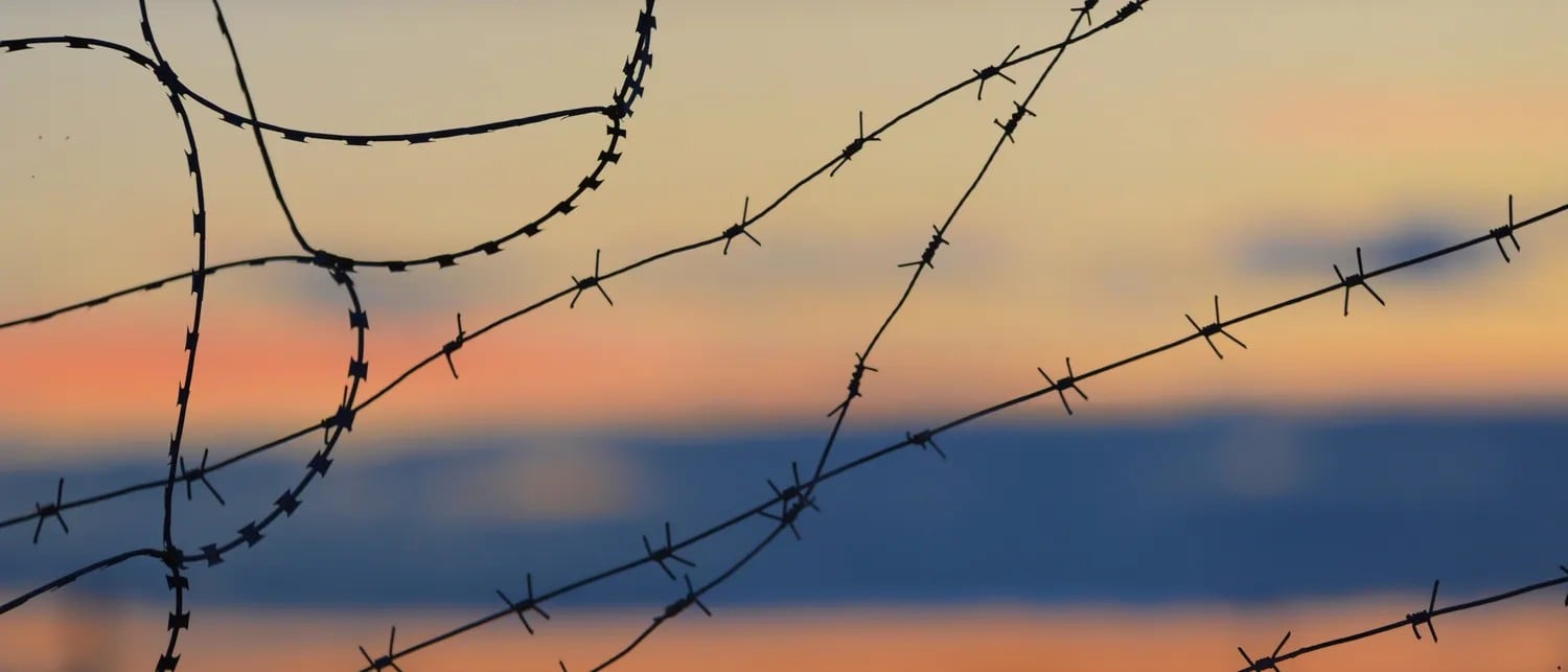 Barbed wire against a sunset sky. Photo credit: Антон Дмитриев