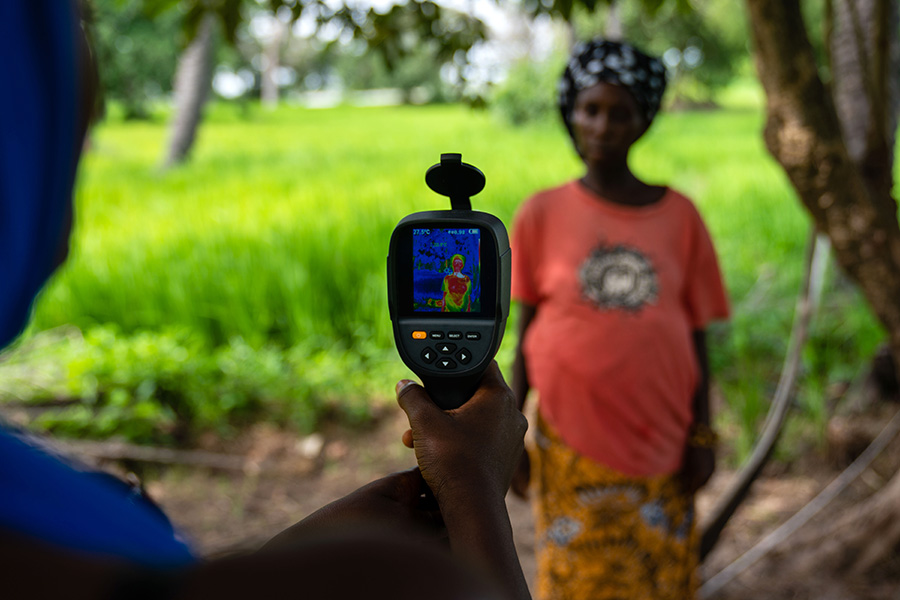 Field worker uses a thermal imaging camera to measure mother and her unborn baby's temperature in Keneba, The Gambia. Credit: Louis Leeson/LSHTM