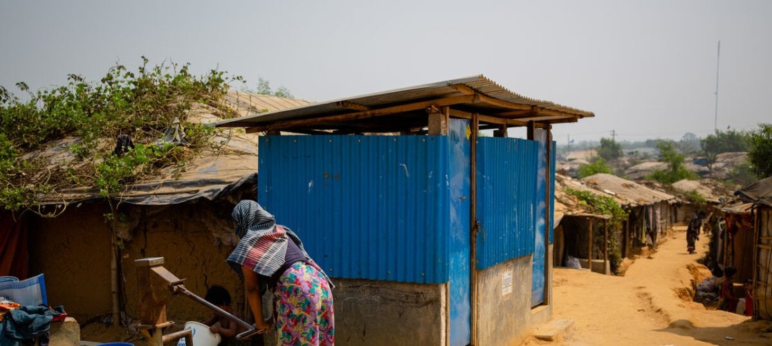 A woman gets water from a pump in a muddy camp in Cox's Bazaar, Bangladesh, on the Myanmar border
