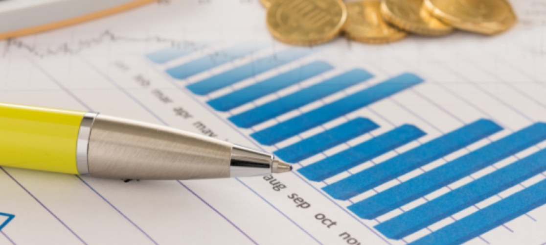 Picture of a pen and pile of coins on top a notebook with a graph