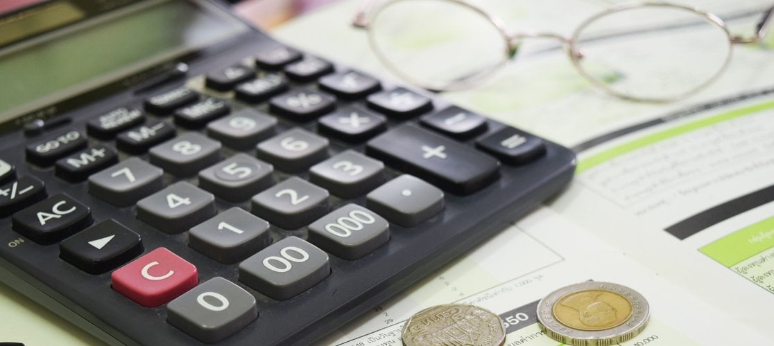 Banner of calculator and coins on table with papers