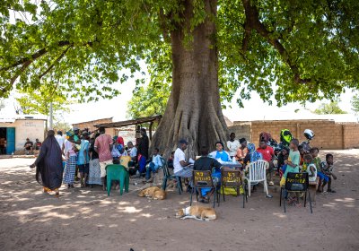 People gathering under a big tree in a local community