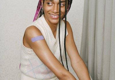 Person smiling while sitting with a purple plaster on the upper arm