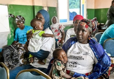 A woman sitting in a crowd, carrying a child.