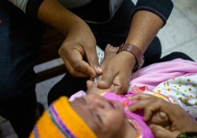 A doctor prepares a dose of measles vaccine for a young child