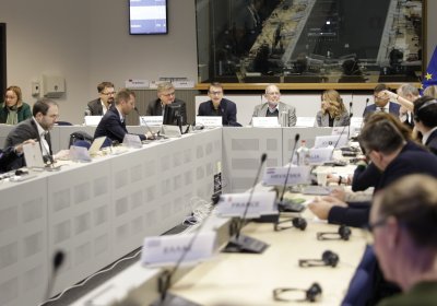 Group of men and women in suits sit around a boardroom table