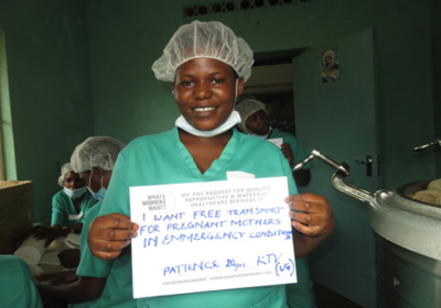 Midwife in hospital holding sign "I want free transport for prgnant mothers in emergency conditions"