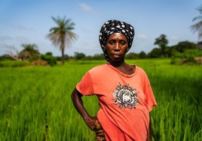 A woman standing on a green farmland in a warm sunny day