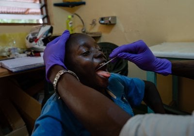 A clinician takes a saliva sample from a young boy, Sibanor, The Gambia.