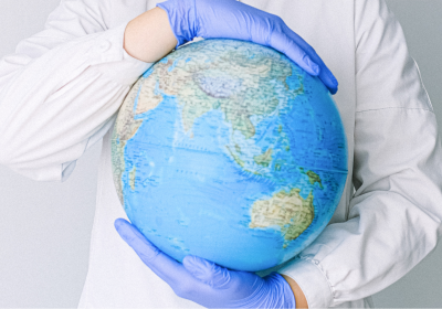 Person With a Face Mask and Latex Gloves Holding a Globe. Photo by Anna Shvets from Pexels