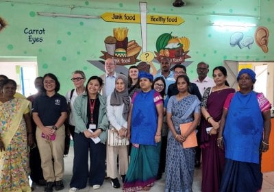 A delegation from the Philippines stands next to workers at a school kitchen in India