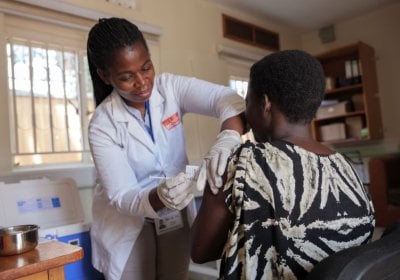 Nurse administering vaccine in arm of clinical trial participant in Uganda