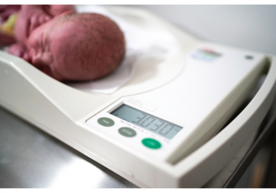 Newborn being weighed on a scale in the hospital. Credit: Canva/FG Trade