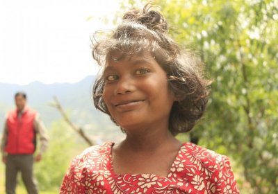 Young girl smiling outside her family home.
