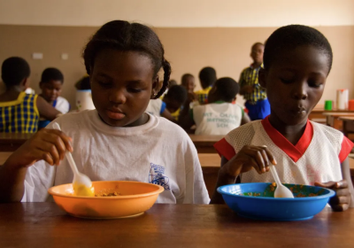 Two black children eat lunch at school from colourful bowls