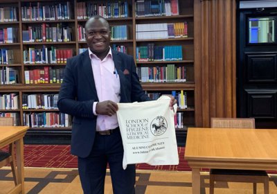 Enock Musungwini in the LSHTM Library holding an LSHTM branded bag