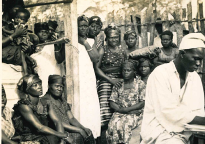 A man in the foreground wearing white while a group of people sit behind him