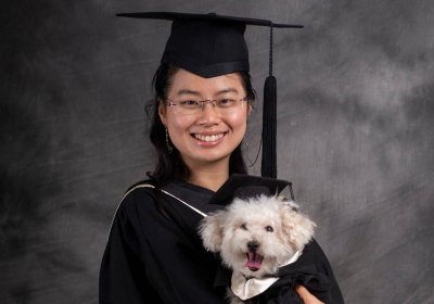 Norris Lau and her dog dressed in graduation gowns and hats