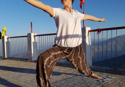 Female striking a yoga pose on a mat on the top of a mountain