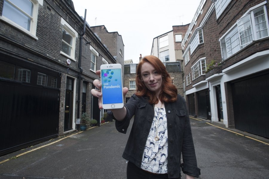 Hannah Fry holding a smartphone displaying the BBC Pandemic App