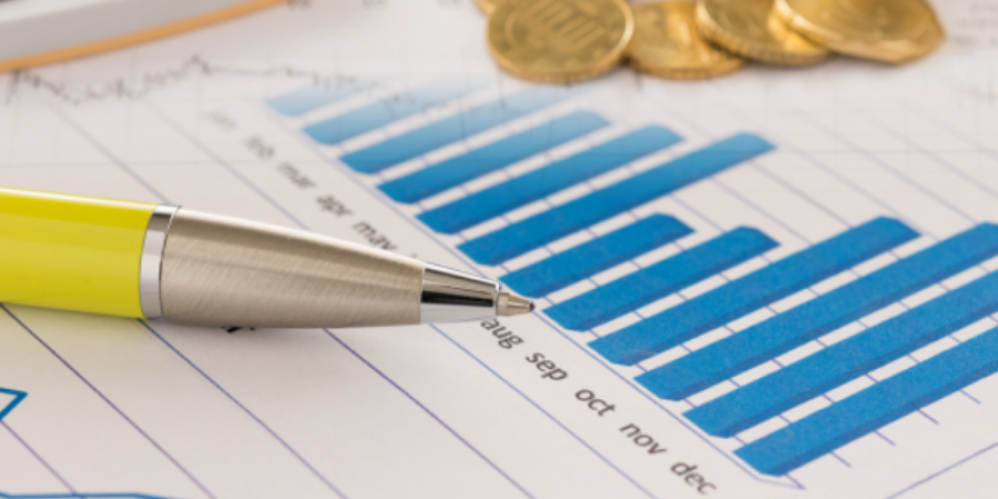 Picture of a pen and pile of coins on top a notebook with a graph