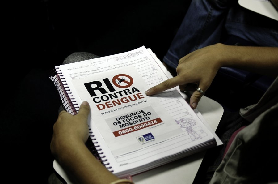 image of someone pointing at a book about dengue in rio