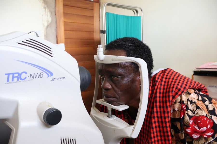 Person receiving a retinal eye examination with a retinal camera in a healthcare clinic.