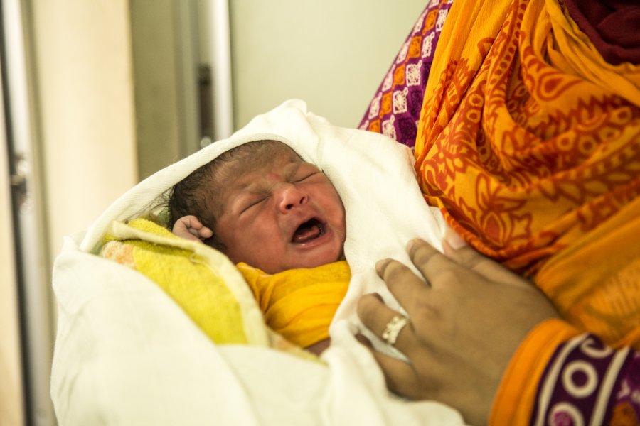 a newborn being held in a rohingya refugee camp