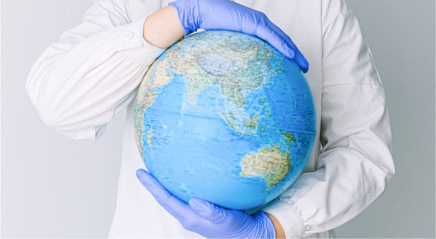 Person With a Face Mask and Latex Gloves Holding a Globe. Photo by Anna Shvets from Pexels